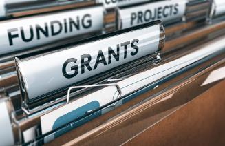 An open office drawer of folders with labels featuring titles that say grants, funding and projects.