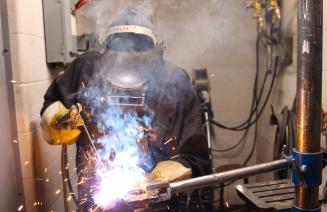 Welder working on a metal project with smoke and sparks flying