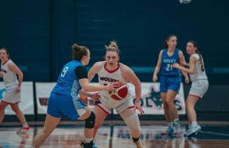 Women's wolves basketball player about to take ball from opponent on court