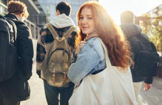 High school student looking over her shoulder as she walks towards a school