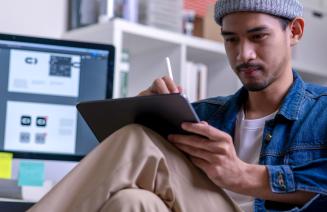 A focused graphic designer sitting and drawing on an electronic tablet