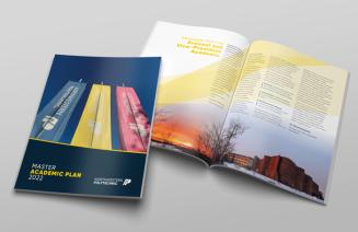 2 copies of the master academic plan on a table, one open and the other closed.