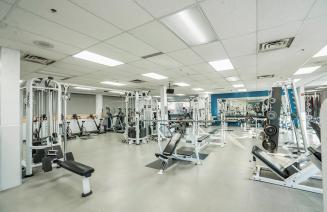 The weight room at grande prairie campus featuring weights, stationary bikes and bench press