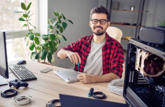 a young IT professional smiling broadly while fixing computer hardware