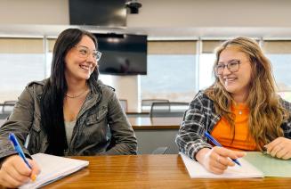 Two happy students studying in a classroom