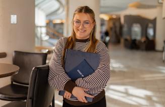 A happy student holding books on campus