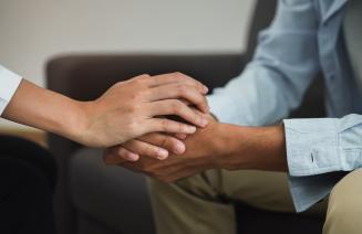 A close up of two peoples hands clasped together in a caring way