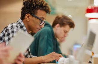 A focused student working on his laptop in a library