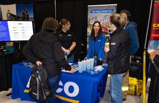 An exhibitor at the Career Fair chatting with visitors to their booth