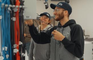 Two student in the electrical lab interacting while connecting wires in an electrical box