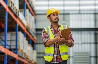 Warehouse manager holding a clipboard observing stock 