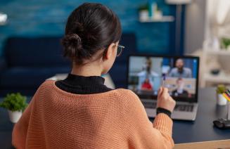 A student facing a laptop and engaging with people in an online meeting
