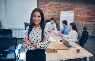 Office Professional standing in the boardroom with colleagues working in the background