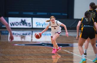Female basketball player dribbling the ball forward towards her opponent