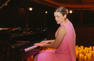 Pianist Michelle Lynne sitting at the piano with candles in the background