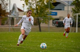 Woles women's soccer player on the pitch dribbling the ball with a teammate behind her