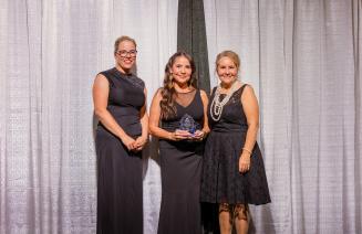 Lois Duke holds the Indigenous Impact Award onstage at the President’s Ball.