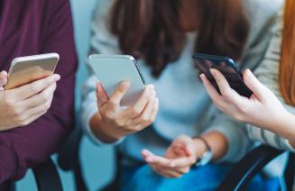 Group of young people using and looking at mobile phone while sitting together