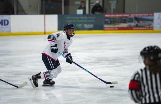 Wolves womens hockey player on the ice about to pass the puck