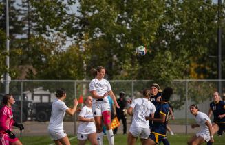 Wolves womens soccer player leaping high above the defense to connect with a powerful header.