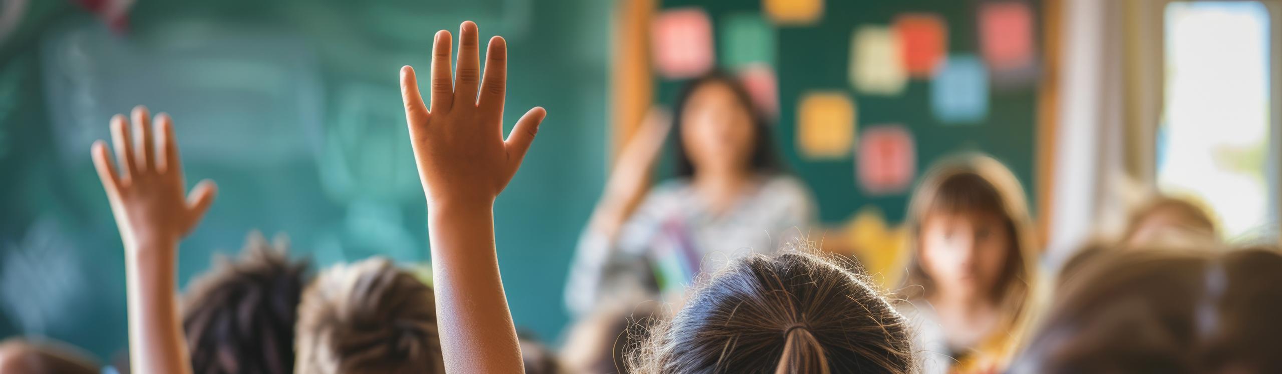 Children in a classroom with hands raised