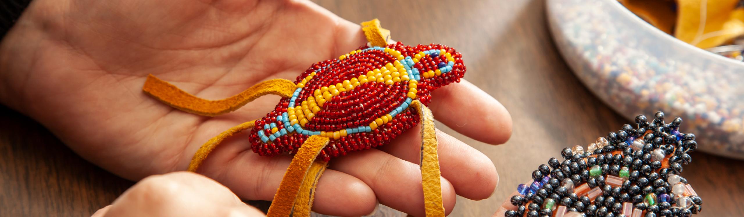 Closeup of a colourful beaded turtle with beading supplies in the background