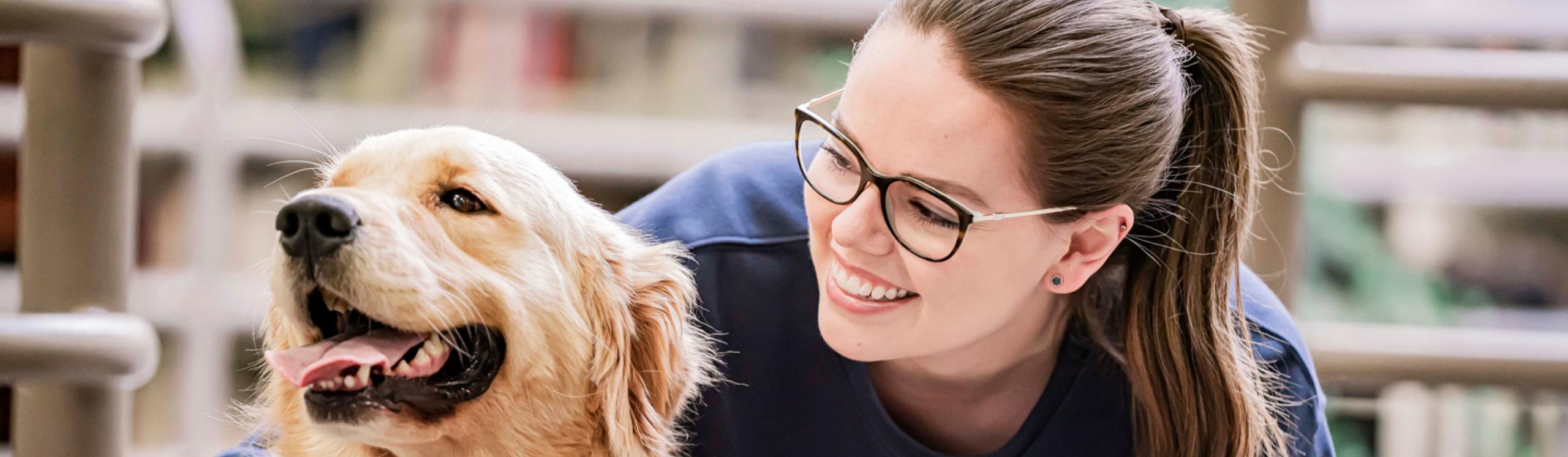 Student petting a therapy dog in the library on Grande Prairie Campus