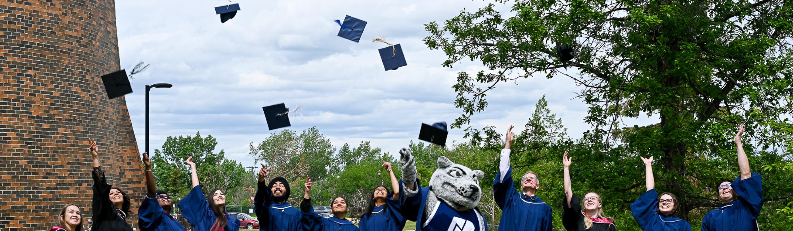 A group of graduates throwing their mortarboards into the air