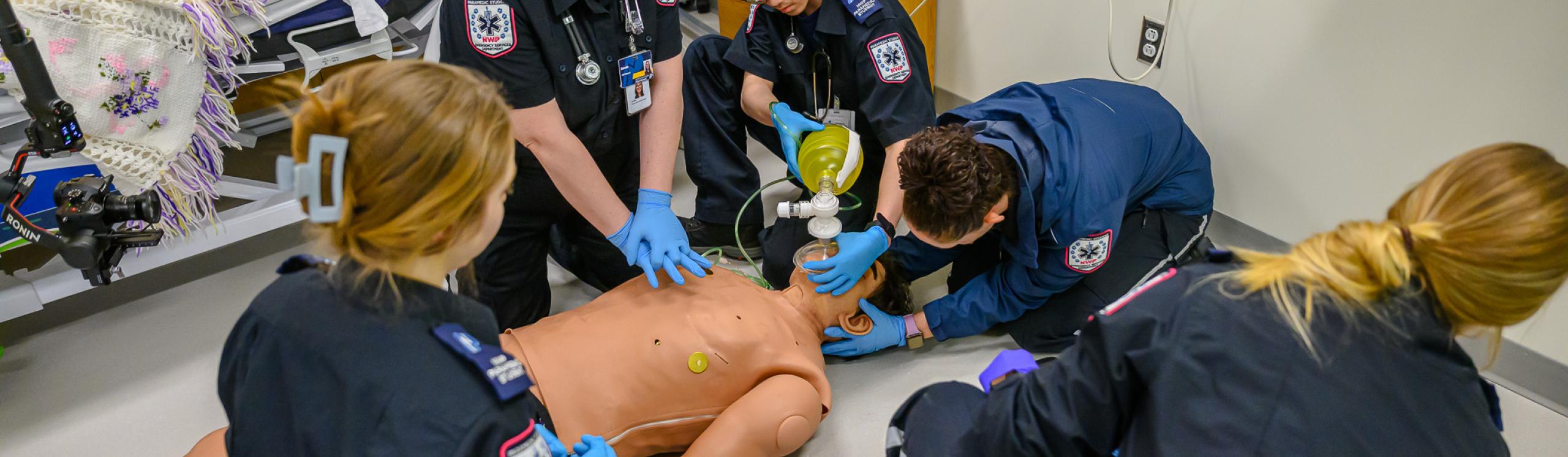 Students in emergency services providing CPR to a dummy in the simulation lab