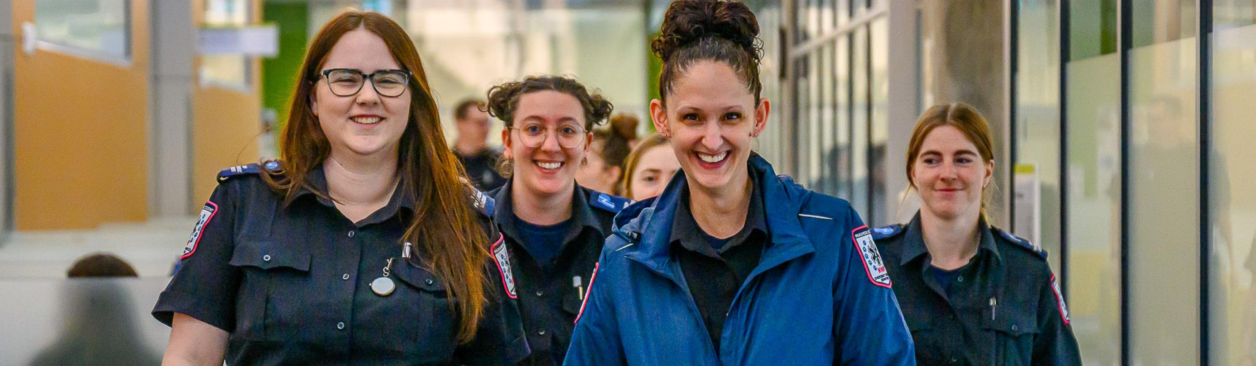 A group of happy emergency services students walking towards the camera