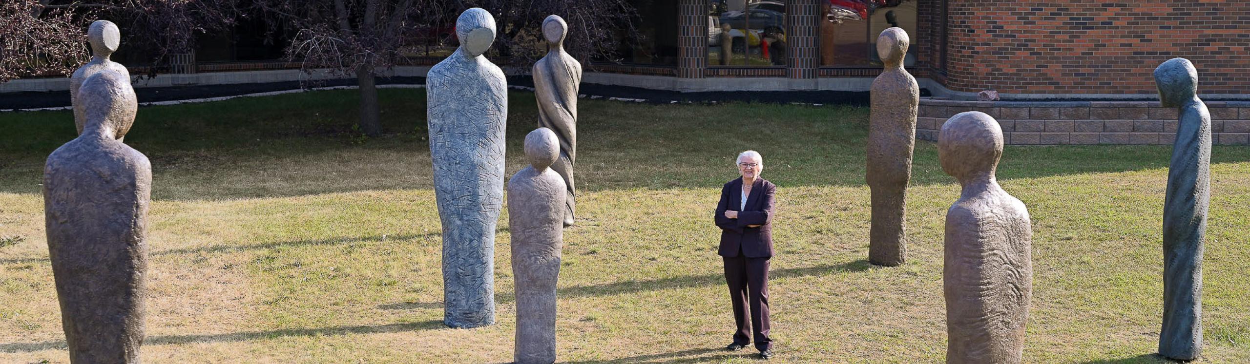 Helena standing among the nine abstract figures that make up the Wisdom installation.