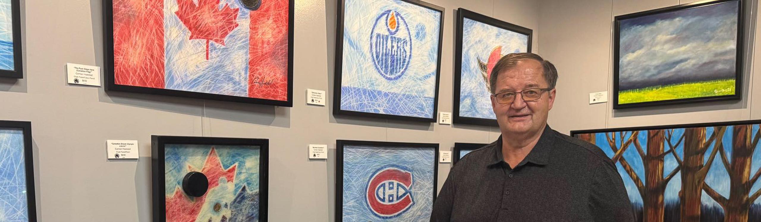 NWP alumni and artist Carmen Haakstad poses proudly alonside a few of his paintings at a recent exhibition.