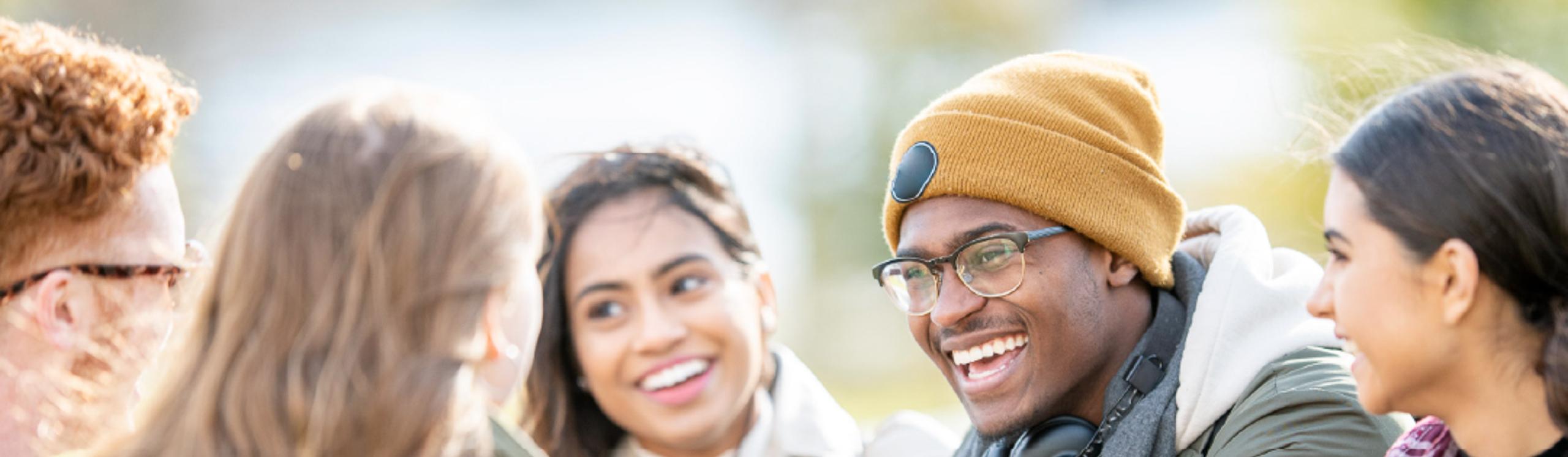 A group of sociable students sitting around a table laughing together