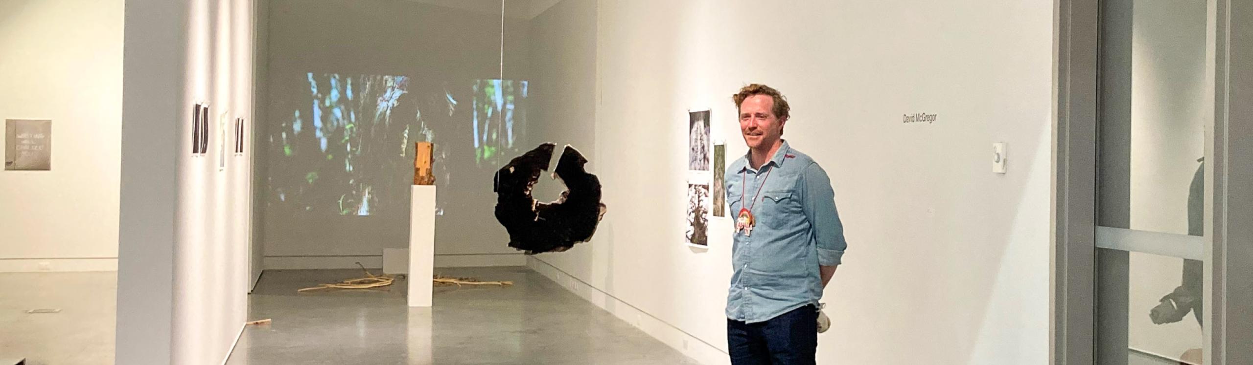 NWP visual arts instructor, David McGregor staning in an art gallery alongside his installation