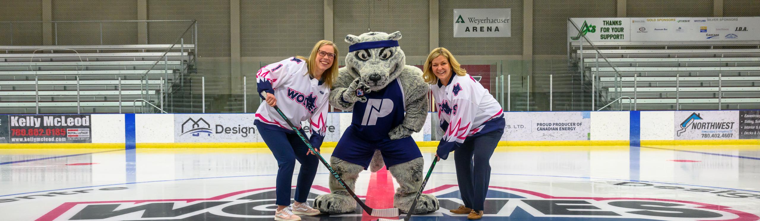 Mayor Clayton and NWP President Vanessa Sheane holding hockey sticks at centre ice with Farley the mascot
