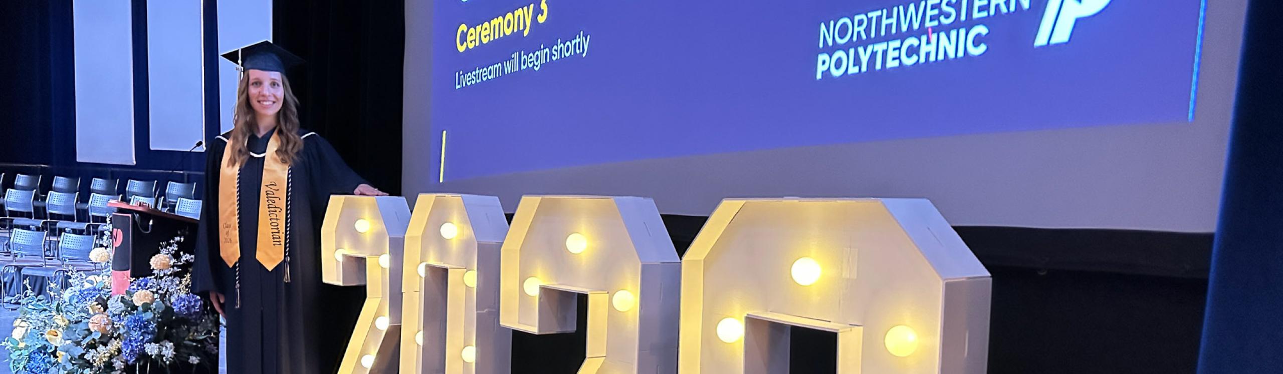 Valedictorian, Courtney Dyck in front of an illuminated 2026 sign